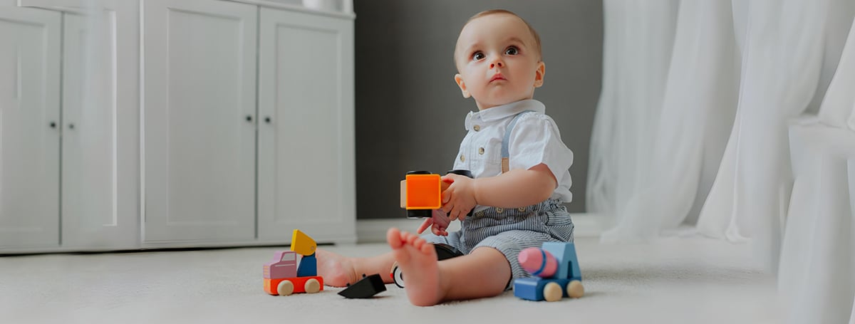 baby sitting floor with toys suprised