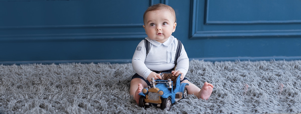 blonde toddler sitting carpet playing with blue car